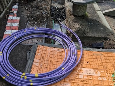 Fibre optic cable coming out of a trench curled up waiting to be installed for the UK gigabit broadband rollout being installed by the internet service providers ISPs across the country.